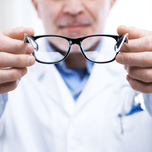 Офтальмолог предлагает пациенту примерить очки в черной оправе