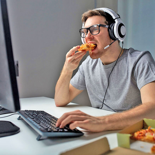 Мужчина ест, сидя за компьютером
